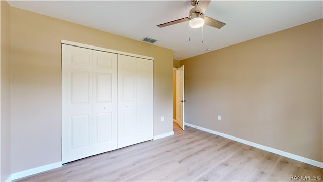 unfurnished bedroom with ceiling fan, light wood-type flooring, and a closet