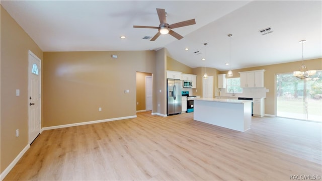 kitchen with stainless steel appliances, vaulted ceiling, a kitchen island, pendant lighting, and white cabinetry