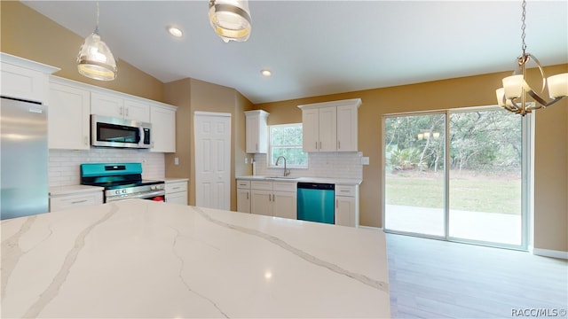 kitchen featuring backsplash, appliances with stainless steel finishes, decorative light fixtures, light stone counters, and white cabinetry