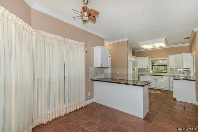 kitchen featuring kitchen peninsula, decorative backsplash, white refrigerator with ice dispenser, and white cabinetry