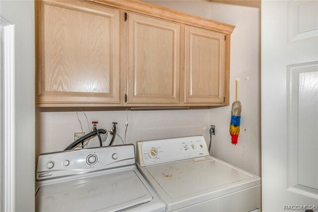 clothes washing area featuring washing machine and dryer and cabinets