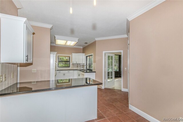 kitchen with sink, kitchen peninsula, crown molding, dark stone counters, and white cabinets