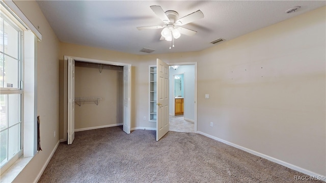 unfurnished bedroom featuring ceiling fan, a closet, and light colored carpet