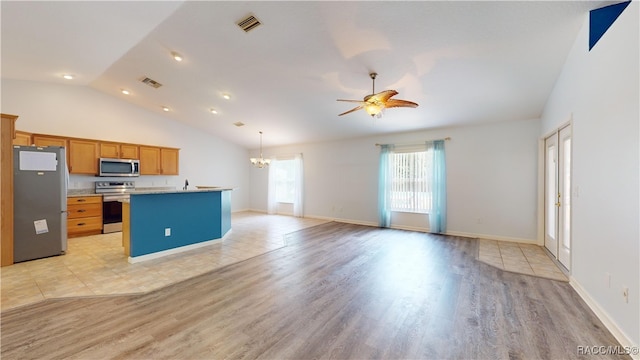 kitchen featuring a kitchen island with sink, ceiling fan with notable chandelier, light hardwood / wood-style flooring, vaulted ceiling, and stainless steel appliances