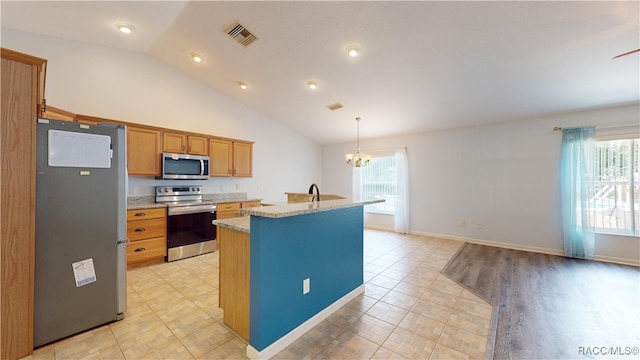 kitchen featuring an inviting chandelier, vaulted ceiling, an island with sink, decorative light fixtures, and stainless steel appliances