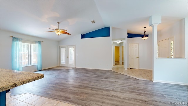 unfurnished living room featuring ceiling fan, french doors, wood-type flooring, and vaulted ceiling