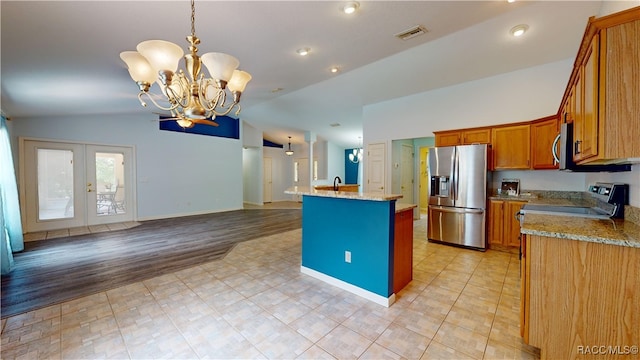 kitchen with lofted ceiling, a kitchen island with sink, light hardwood / wood-style flooring, stainless steel appliances, and a chandelier