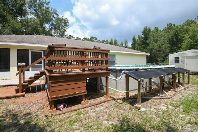 rear view of property with a swimming pool side deck and a shed