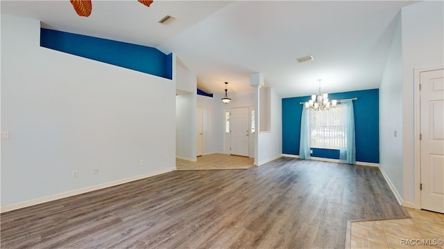 interior space featuring ceiling fan with notable chandelier, decorative columns, wood-type flooring, and vaulted ceiling