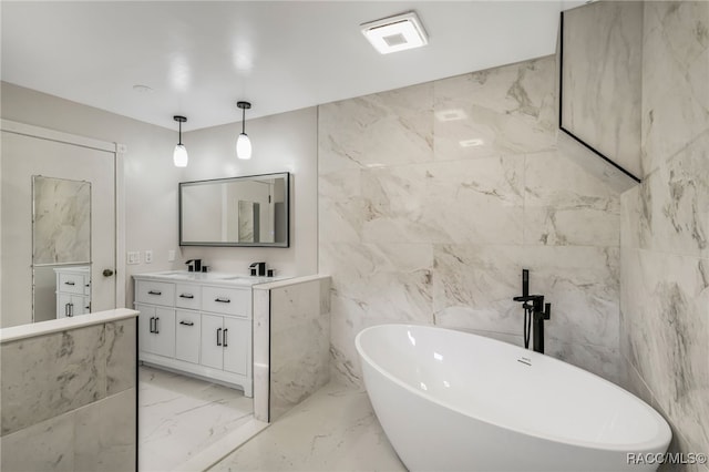 bathroom with visible vents, marble finish floor, tile walls, a freestanding bath, and double vanity