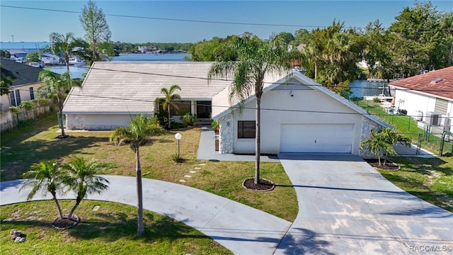 view of front of house featuring an attached garage, fence, stucco siding, a front lawn, and driveway
