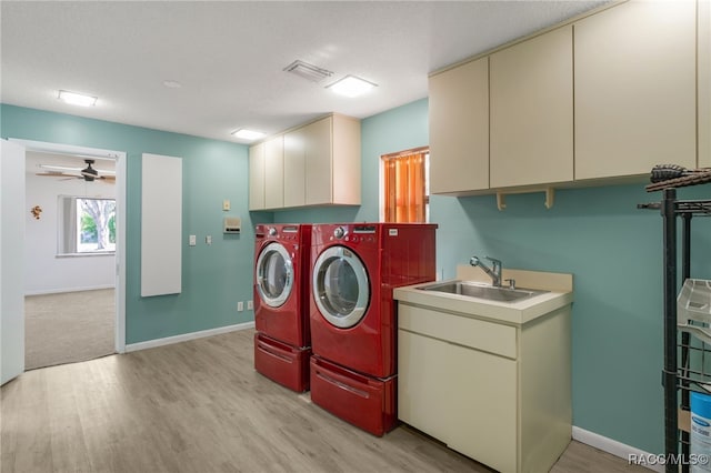 laundry room featuring visible vents, a sink, light wood finished floors, cabinet space, and washer and clothes dryer