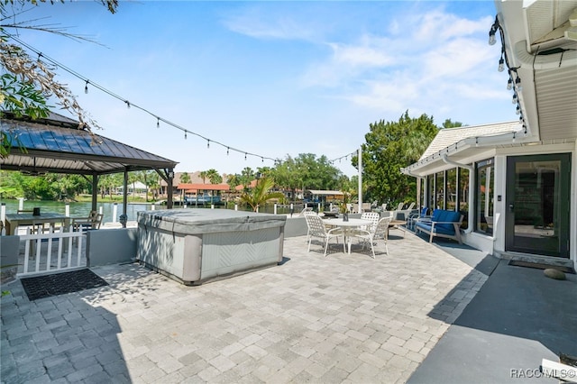 view of patio featuring outdoor dining space, a hot tub, and a gazebo