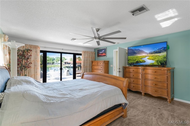 bedroom featuring a textured ceiling, access to exterior, a ceiling fan, and visible vents