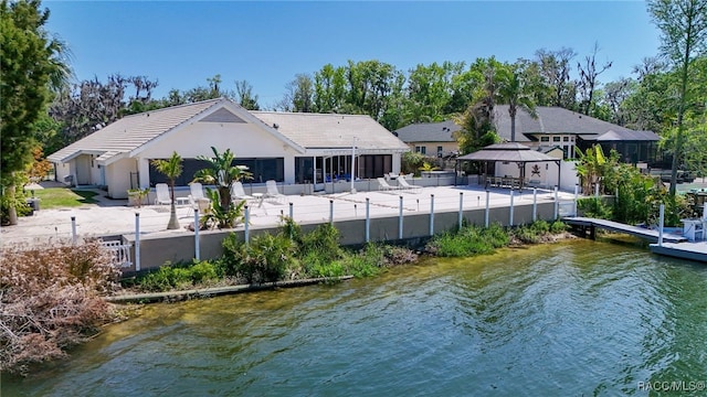 rear view of house featuring a patio, a water view, a gazebo, a tiled roof, and fence