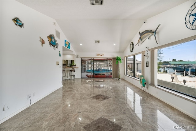unfurnished living room with visible vents, high vaulted ceiling, and marble finish floor