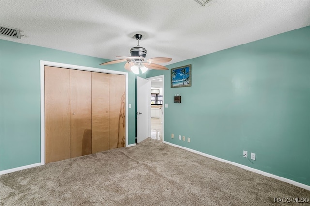 unfurnished bedroom with a textured ceiling, a closet, carpet flooring, and visible vents