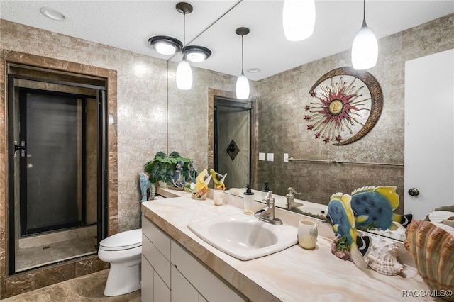 bathroom with tile walls, toilet, a shower stall, and vanity