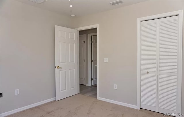 unfurnished bedroom with a closet and light colored carpet