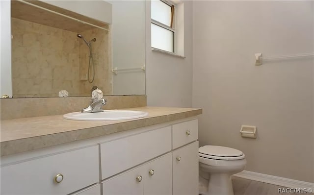 bathroom featuring tiled shower, vanity, and toilet