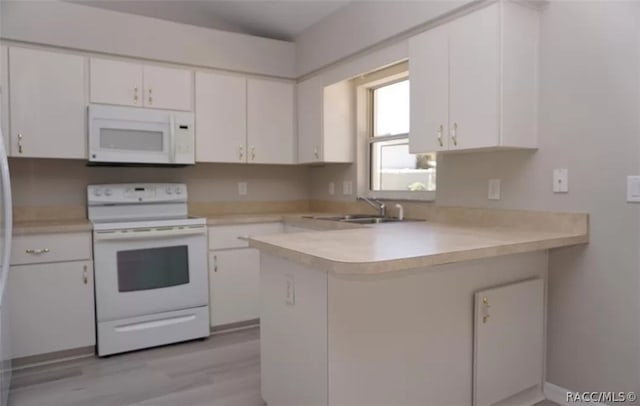 kitchen with kitchen peninsula, white appliances, white cabinetry, and sink