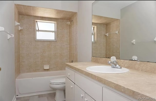 full bathroom featuring vanity, tiled shower / bath combo, and toilet