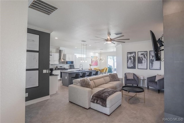 tiled living room featuring ornamental molding, sink, and ceiling fan with notable chandelier