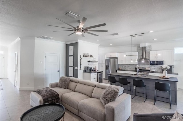 living room with crown molding, ceiling fan, a textured ceiling, light tile patterned flooring, and beverage cooler