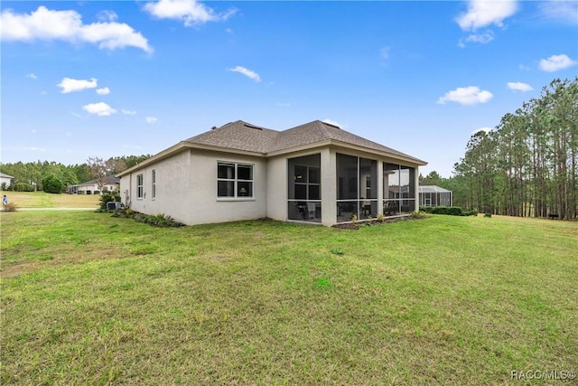 rear view of house featuring a sunroom and a lawn