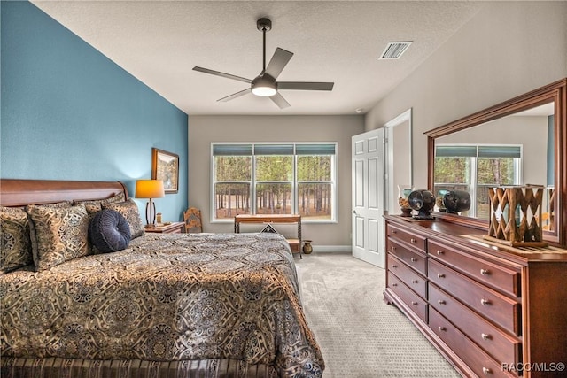 carpeted bedroom featuring ceiling fan, multiple windows, and a textured ceiling