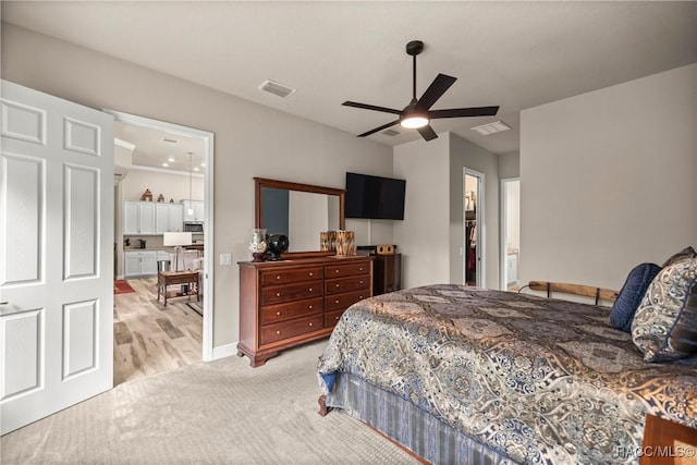 bedroom with light carpet, ensuite bath, and ceiling fan