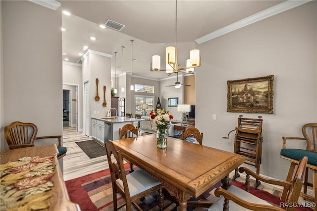 dining space with sink, light hardwood / wood-style flooring, ornamental molding, and ceiling fan