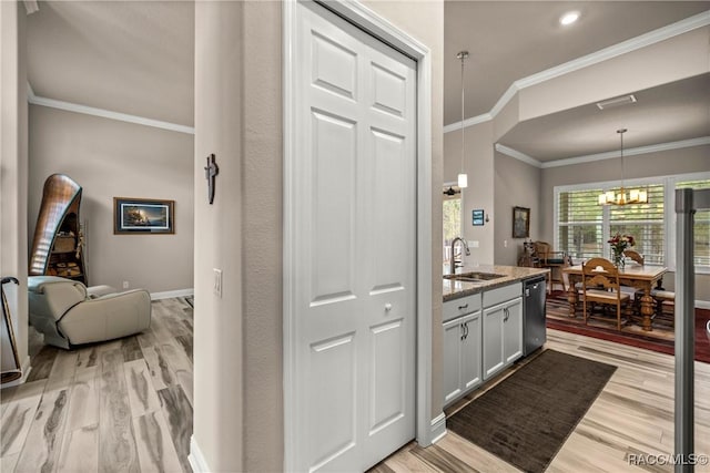 kitchen with sink, dishwasher, light stone counters, light hardwood / wood-style floors, and decorative light fixtures