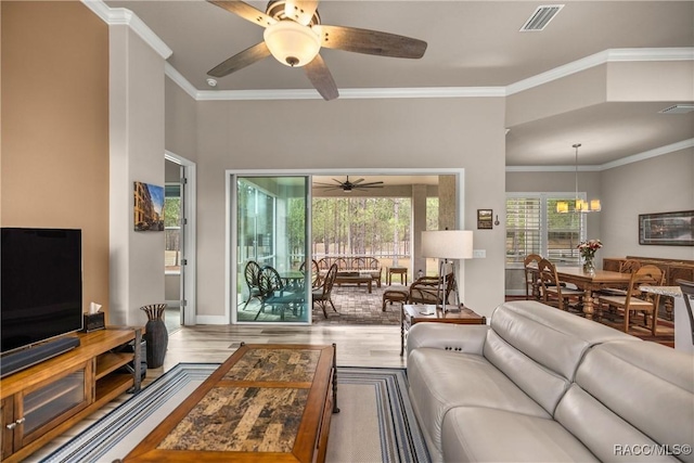 living room with ornamental molding, ceiling fan with notable chandelier, and light wood-type flooring