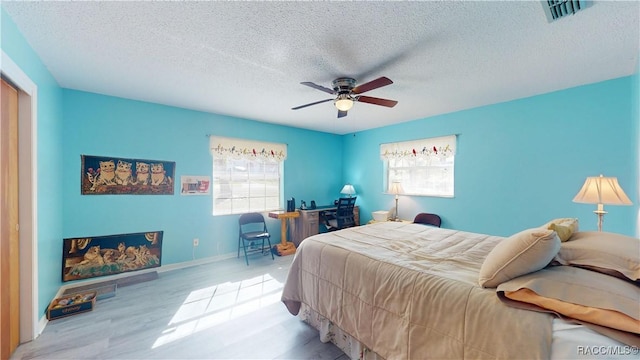 bedroom featuring visible vents, a textured ceiling, wood finished floors, and a ceiling fan