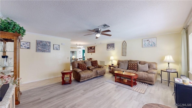 living area with visible vents, light wood-style flooring, a ceiling fan, ornamental molding, and a textured ceiling