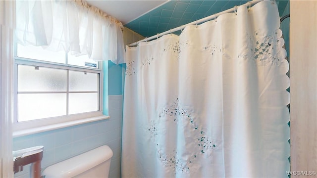 full bathroom featuring curtained shower, tile walls, and toilet