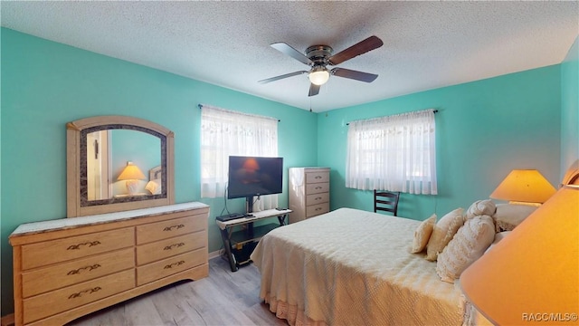 bedroom featuring light wood-style floors, ceiling fan, and a textured ceiling