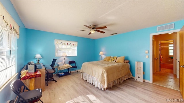 bedroom featuring visible vents, multiple windows, and wood finished floors