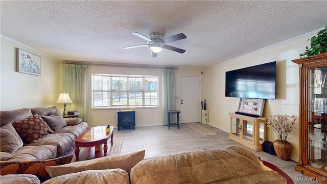 living area featuring wood finished floors, ceiling fan, a wood stove, and ornamental molding