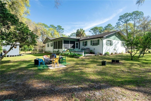 rear view of house featuring a patio area, a lawn, and a sunroom