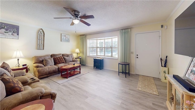 living area with ornamental molding, a ceiling fan, a textured ceiling, wood finished floors, and a wood stove