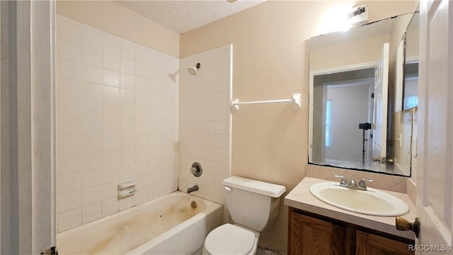 full bathroom featuring toilet, vanity, a textured ceiling, and tiled shower / bath