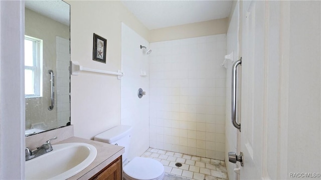 bathroom featuring tile patterned flooring, vanity, tiled shower, and toilet