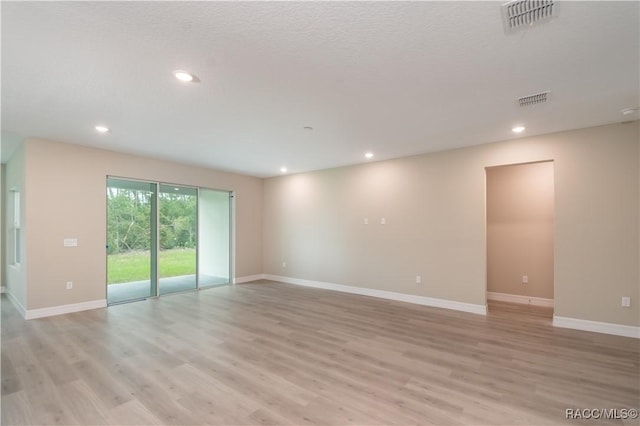 unfurnished room featuring a textured ceiling and light wood-type flooring