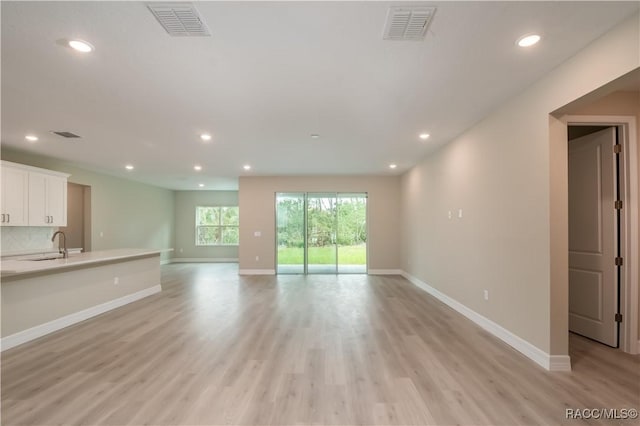 unfurnished living room featuring sink and light hardwood / wood-style flooring