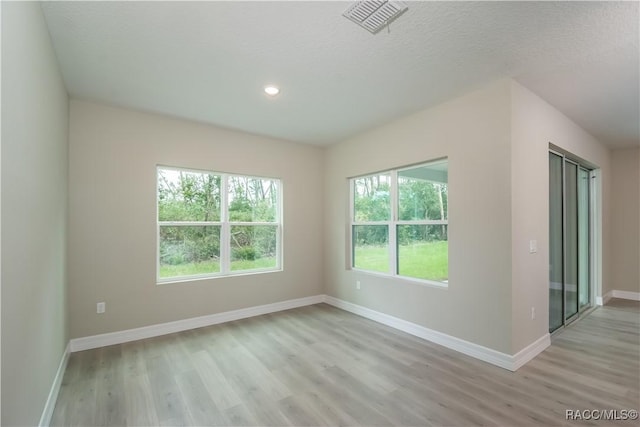 unfurnished room featuring a textured ceiling and light wood-type flooring