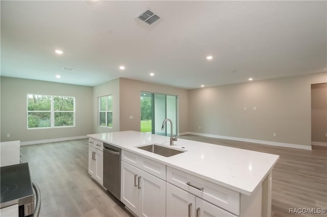 kitchen with appliances with stainless steel finishes, white cabinetry, sink, a kitchen island with sink, and light wood-type flooring