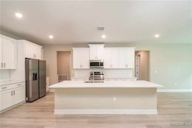 kitchen featuring appliances with stainless steel finishes, a center island with sink, and white cabinets