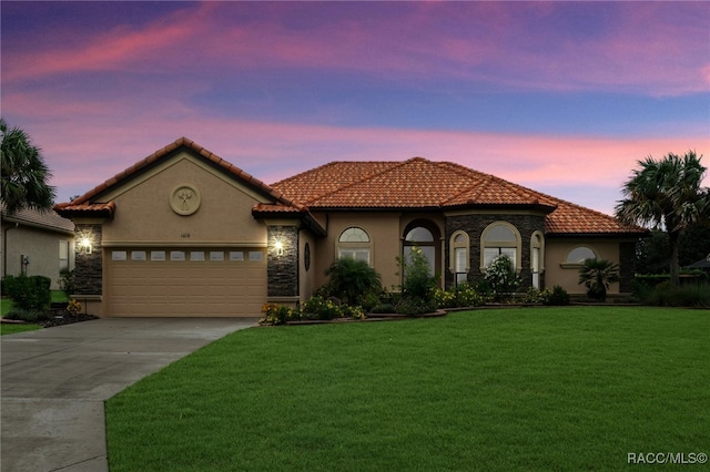 mediterranean / spanish-style home with a lawn and a garage